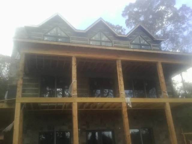 Dormers and porch framing on a large log home under construction — Roof Coating work by our crew in Rodessa