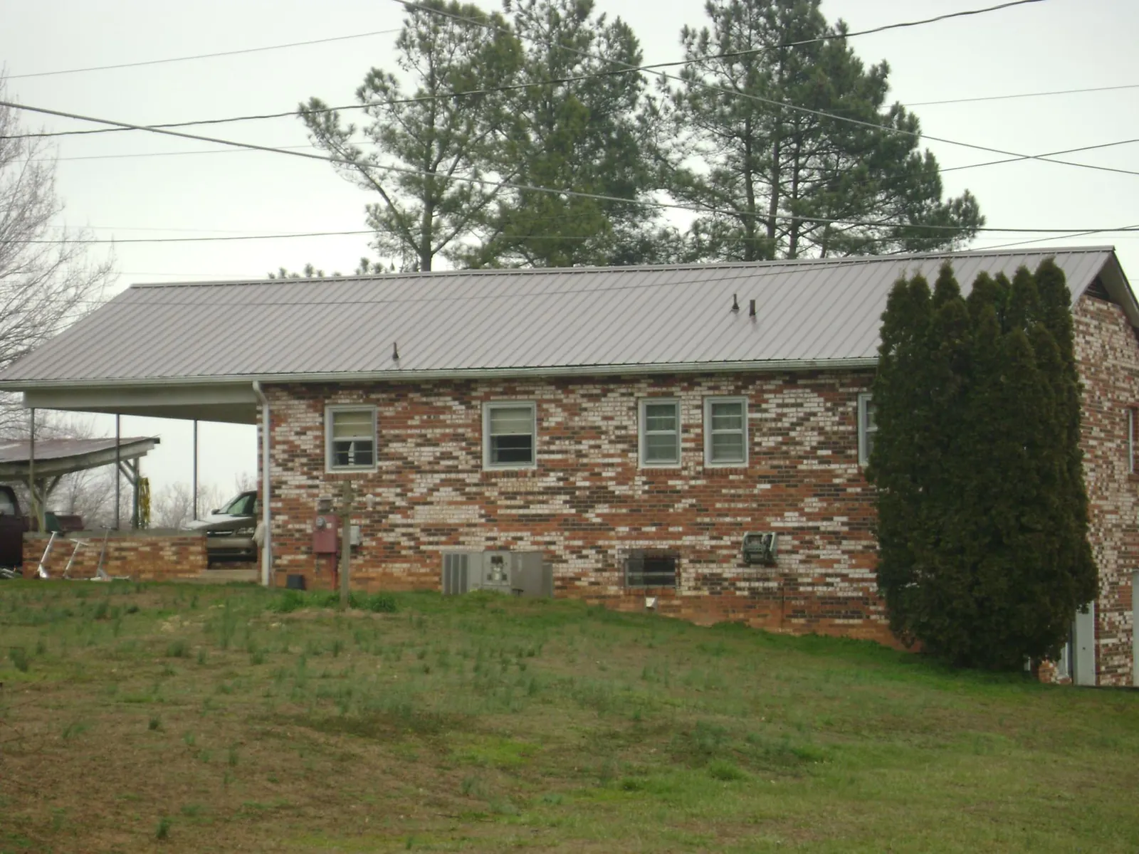Gray metal roof on a brick split level home with a carport in Rodessa