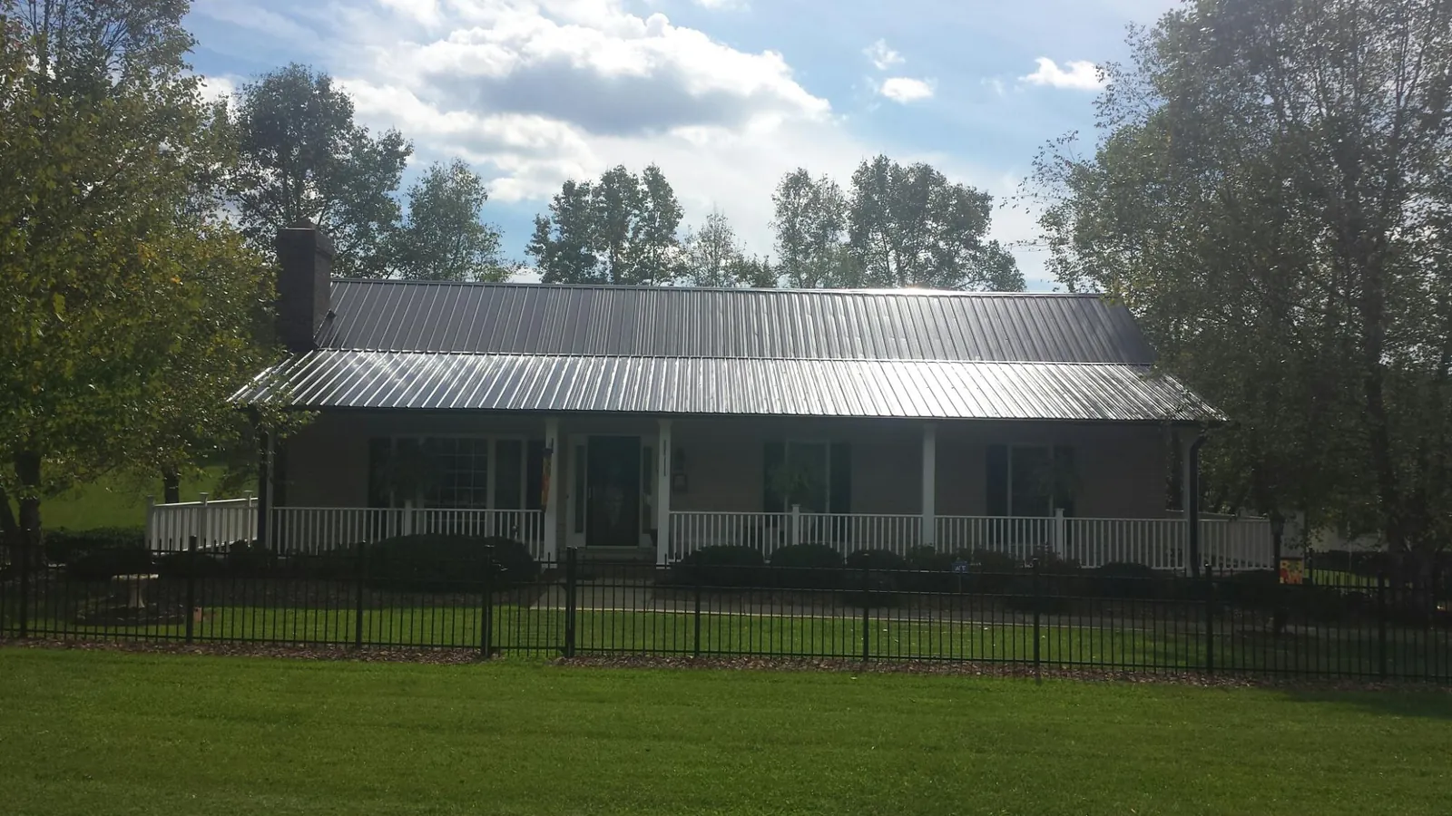 Gray metal roof on a brick ranch with a full width front porch — Gutter Guard Installation work by our crew in Rodessa