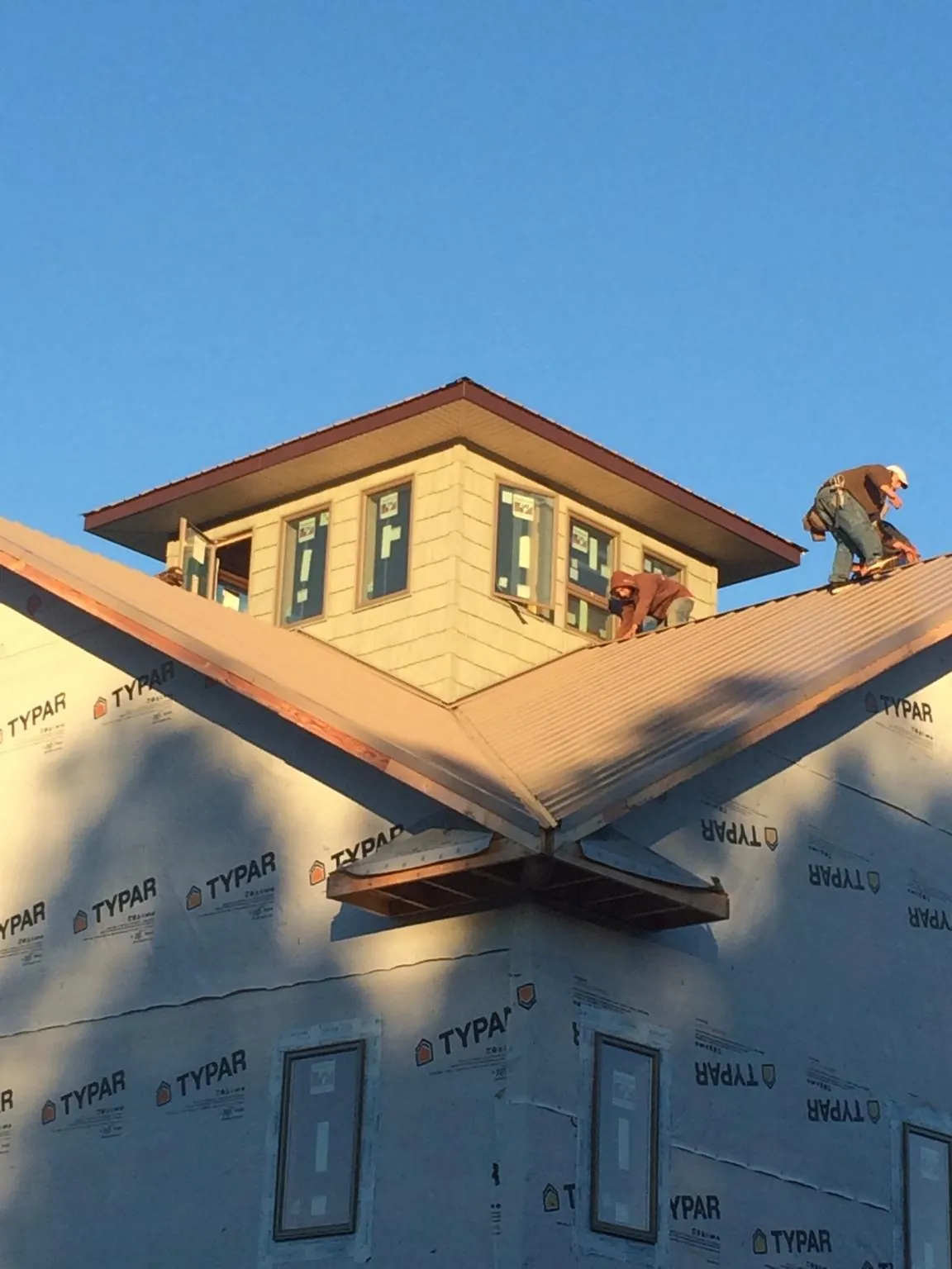 Roofers working around a rooftop cupola on a new metal roof at sunset — Roof Waterproofing in Rodessa by Roofing Brothers